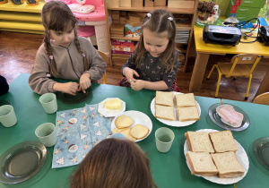 Dziewczynka siedzi przy stole i przygotowuje tosty.