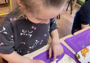 Dziewczynka przy stole zwija rogalki.