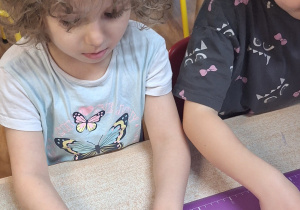 Dziewczynka przy stole zwija rogalki.