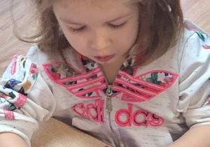 Dziewczynka przy stole zwija rogalki.