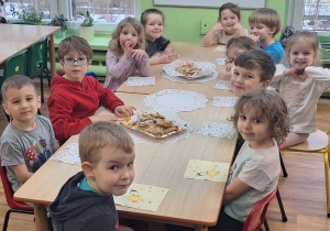 Dzieci siedzą przy stole na którym stoją rogaliki.