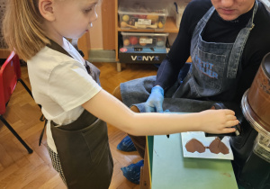 Dziewczynka napełnia formy czekoladą.