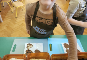 Chłopiec wkłada do czekolady dodatki.