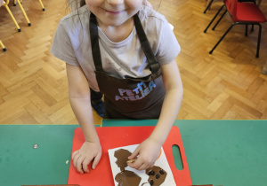Dziewczynka wkłada do czekolady dodatki.