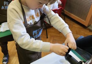 Chłopiec napełnia formy czekoladą.