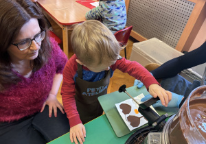 Chłopiec wypełnia formy czekoladą.