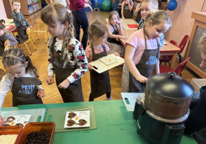 Dziewczynka wkłada do czekolady dodatki.