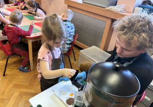 Dziewczynka wypełnia formy czekoladą.