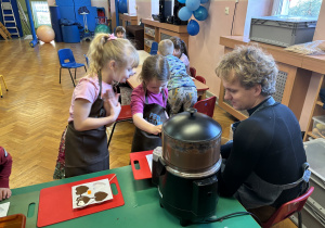 Dziewczynka wypełnia formy czekoladą.