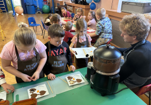 Dzieci wkładają do czekolady dodatki.