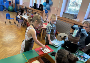 Dziewczynka wkłada do czekolady dodatki.