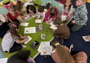 Dzieci siedzą na podłodze i rysują koty.