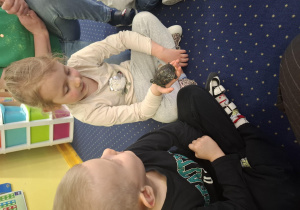 dzieci siedzą w kole na dywanie, podają sobie małego żółwia