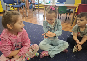 dzieci siedzą w kole na dywanie, podają sobie małego żółwia