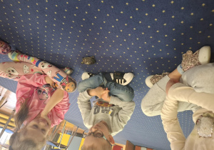 dzieci siedzą w kole na dywanie, podają sobie małego żółwia