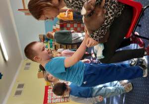 chłopiec głaszcze skunksa, który siedzi na kolanach pani