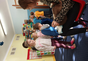 dzieci przygladają się skunksowi w brązowym kolorze, który siedzi na kolanach pani