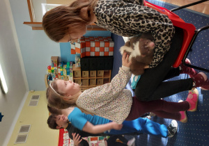 dziewczynka głaszcze skunksa, który siedzi na kolanach pani