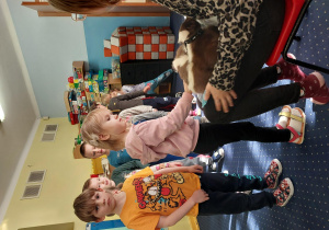 dziewczynka głaszcze skunksa, który siedzi na kolanach pani