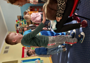 chłopiec głaszcze skunksa, który siedzi na kolanach pani