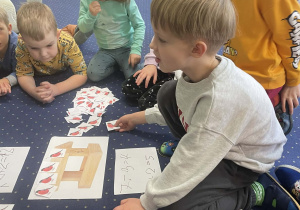 Dzieci siedzą na dywanie i przeliczają.