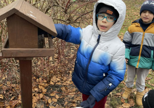Dzieci dokarmiają ptaki w ogrodzie przedszkolnym.