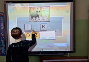 Chłopiec wykonuje zadanie na tablicy interaktywnej.