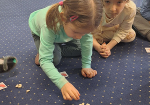 Dzieci siedzą na dywanie i przeliczają.