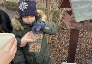Dzieci dokarmiają ptaki w ogrodzie przedszkolnym.