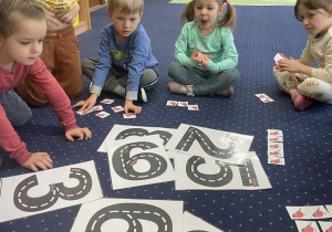 Dzieci siedzą na dywanie i przeliczają.
