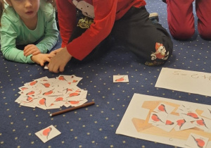 Dzieci siedzą na dywanie i przeliczają.