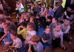 Dzieci siedzą na sali i obserwują aktorów.