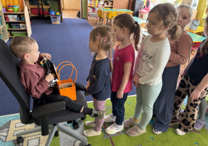 Dzieci ustawione w rzędzie podchodzą do chłopca.