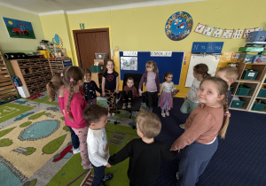 Dzieci ustawione w kole śpiewają "100 lat".