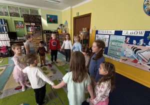 Dzieci ustawione w kole śpiewają "100 lat!".