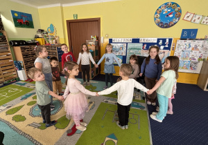 Dzieci ustawione w kole śpiewają "100 lat!".