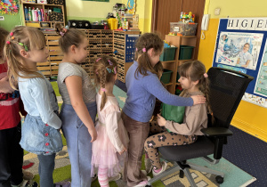 Dzieci ustawione w rzędzie podchodzą do dziewczynki i składają jej życzenia.