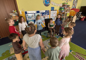 Dzieci ustawione w kole śpiewają "100 lat!".