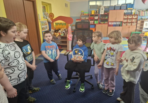 chłopiec świętuje urodziny, dzieci z grupy składaja mu życzenia, chłopiec częstuje cukierkami