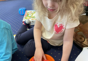 Na dywanie dziewczynka przelicza figurki.