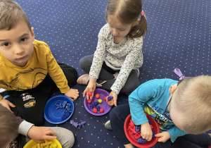 Na dywanie dzieci przeliczają elementy.