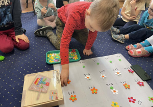 Dzieci na dywanie doskonalą umiejętność dodawania.