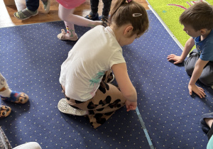 Dzieci mierzą długość dywanu.