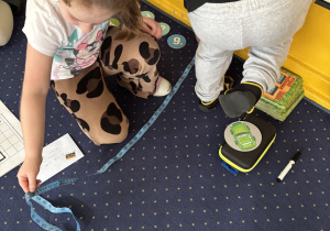 Dzieci mierzą długość dywanu.