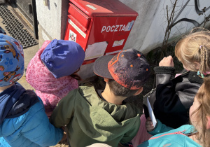 Dzieci wrzucają do skrzynki pocztowej list dla koleżanki.