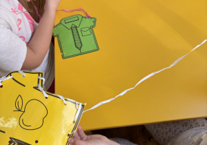 Dzieci siedzą przy stolikach i szyją ubrania.