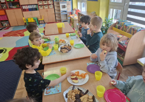 dzieci przy stolikach świętują urodziny kolegi