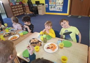 dzieci przy stolikach świętują urodziny kolegi