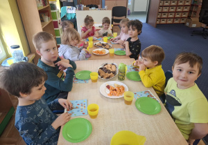 dzieci przy stolikach świętują urodziny kolegi