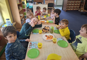 dzieci przy stolikach świętują urodziny kolegi